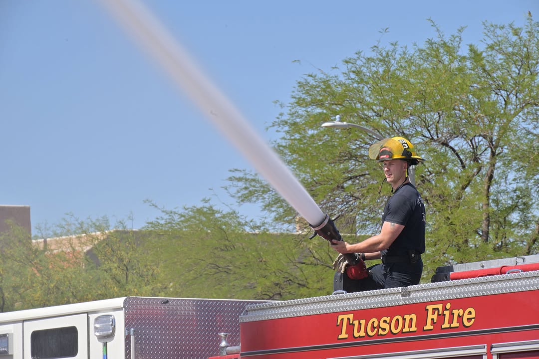 A firefighter sprays students with the hose on the fire truck
