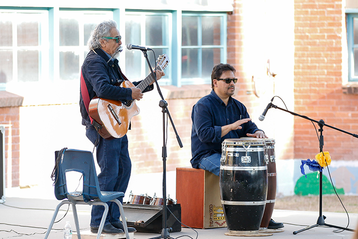 A man plays guitar and another man plays drums on stage