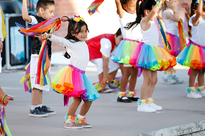 A group of students dance in colorful skirts